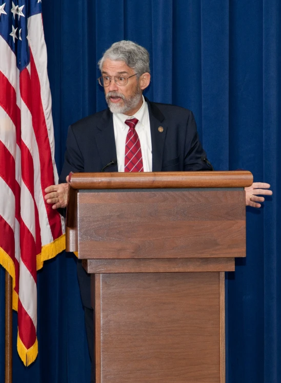 a man wearing a suit stands at a podium