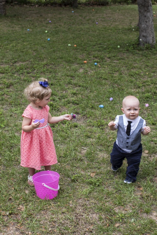 two babies playing outside with one baby on the other