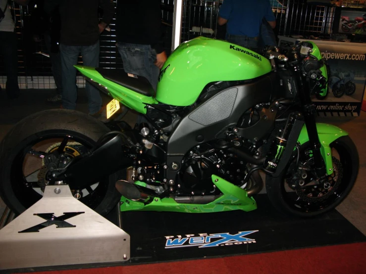 a green motorcycle is parked on display in a building