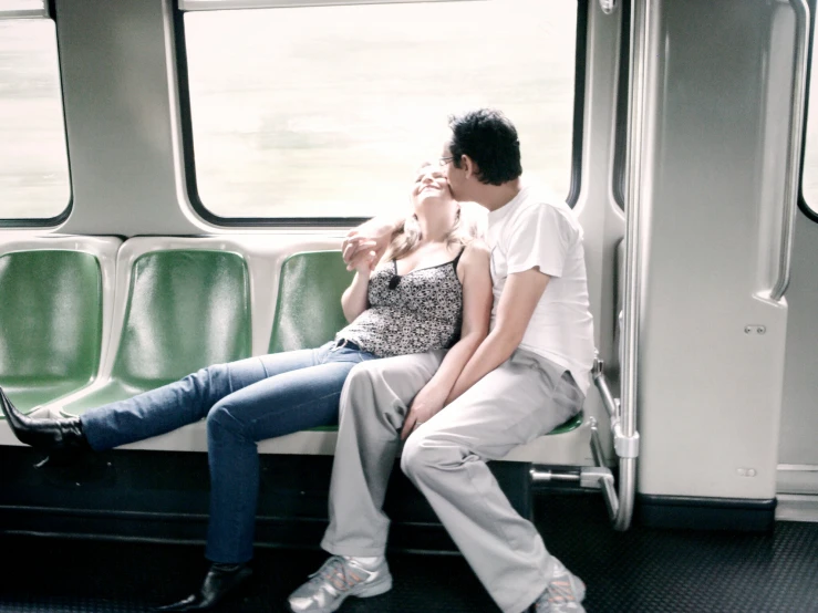 two people sitting on a subway car with their backs against one another