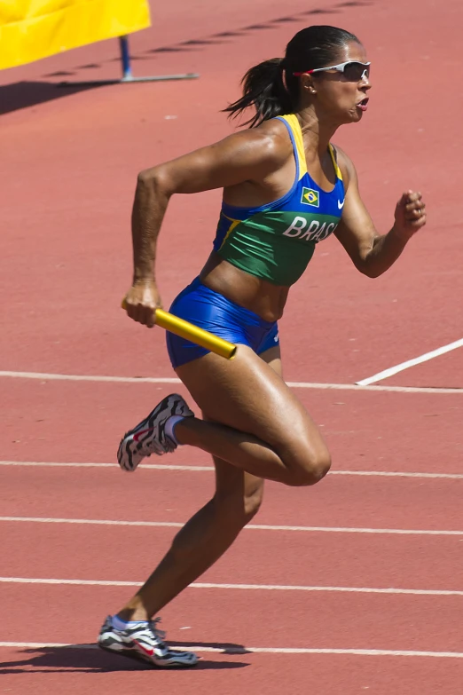 a female athlete in blue running while holding a yellow pole