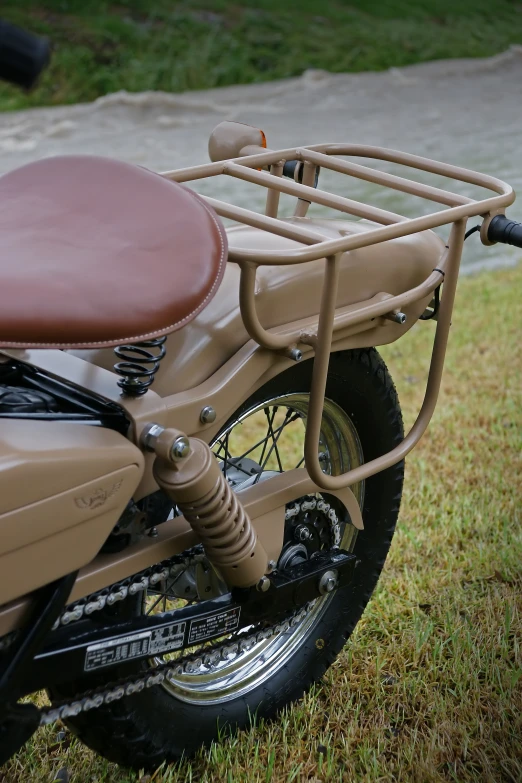 a motorcycle parked in grass with a brown seat