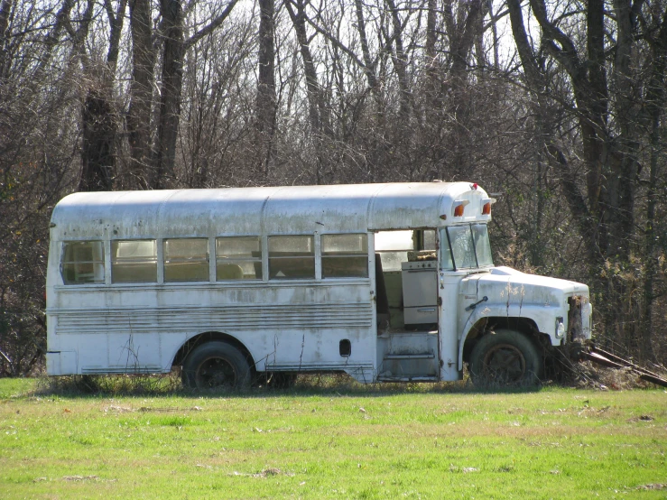 an old school bus sitting in the middle of a field