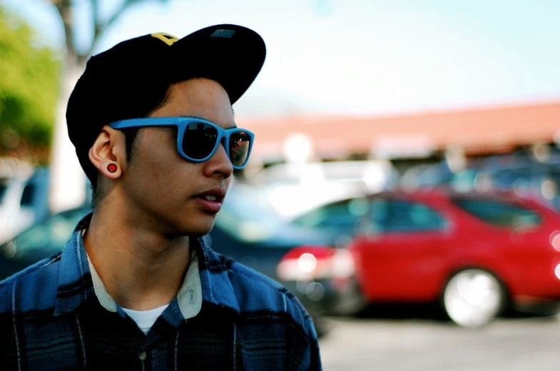 a young man wearing sunglasses and a black cap in the city