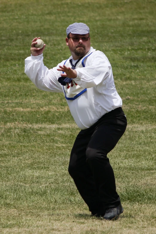 man in all white throwing ball with arms extended