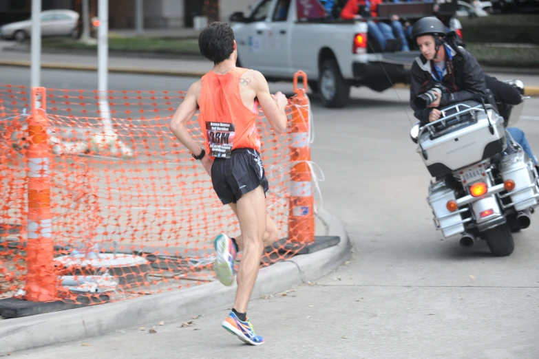 a runner runs down the road near an orange fence