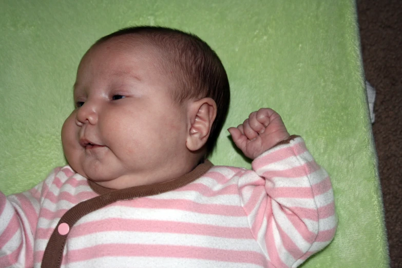 a baby with its head propped up and wearing striped pajamas