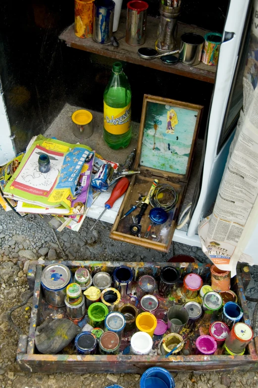 a variety of paints and bottles are laid out on the ground