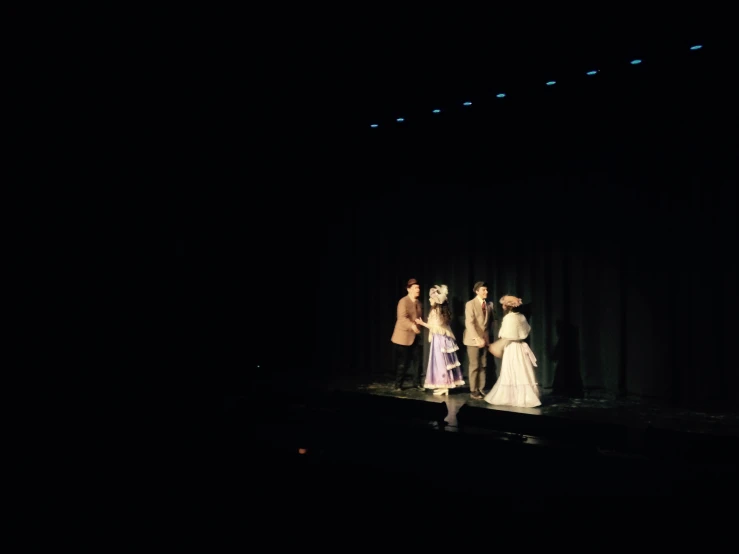 five people in costumes walking down a stage