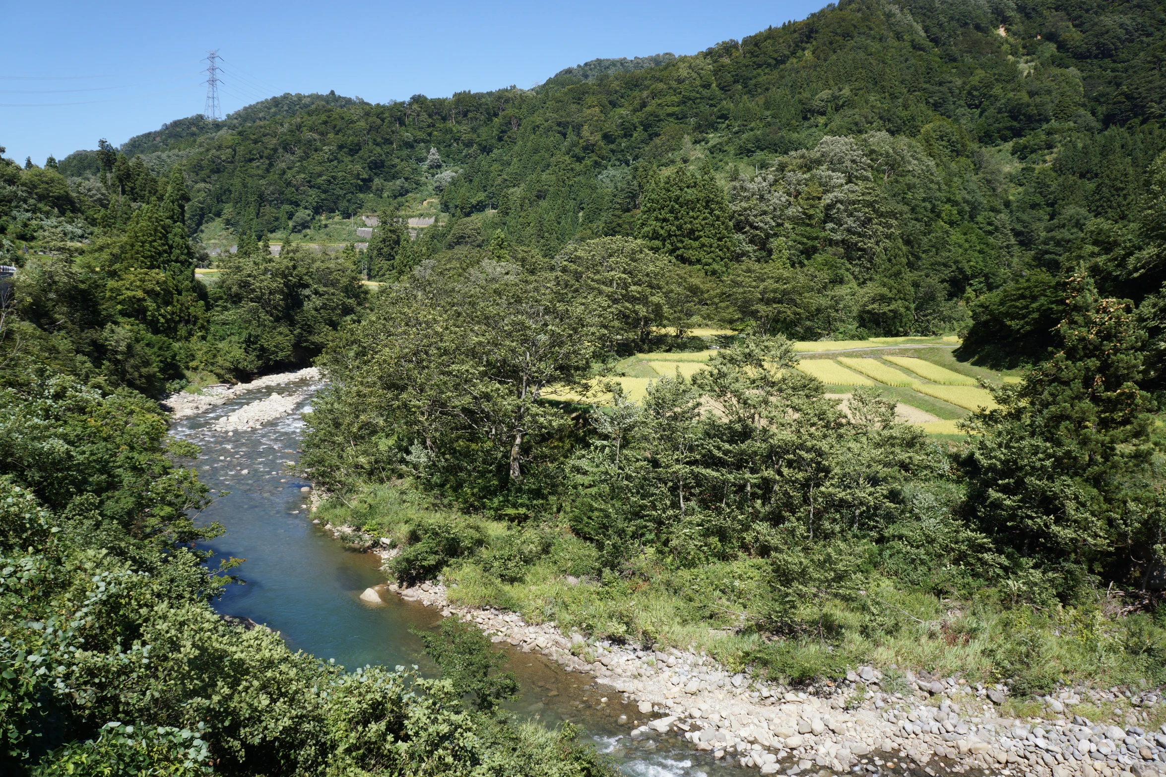 the water is running underneath the mountains by the grass and trees