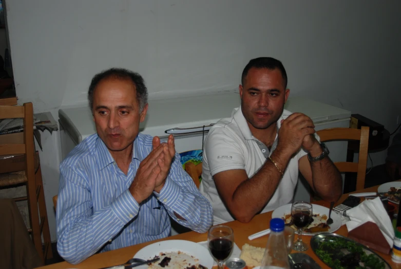 the men are sitting at a table praying