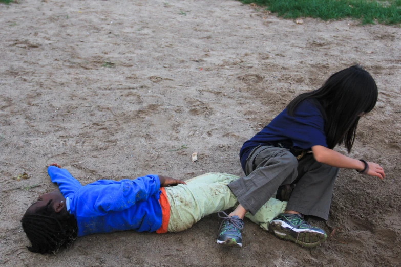 a boy is laying on the ground while a  is laying down on the ground