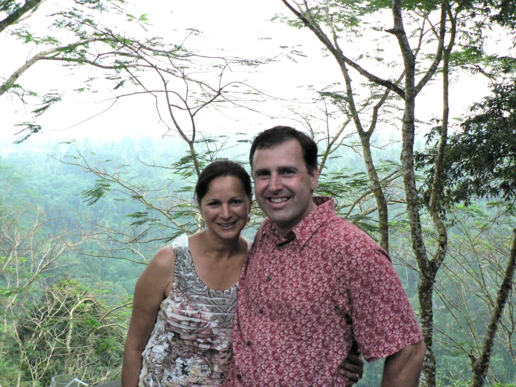 man and woman standing close to each other on a hillside