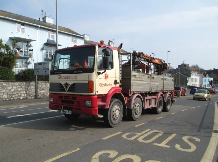 a large truck on a city street lined with cars