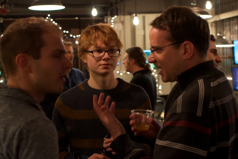 two men and a woman at a party with lights around them