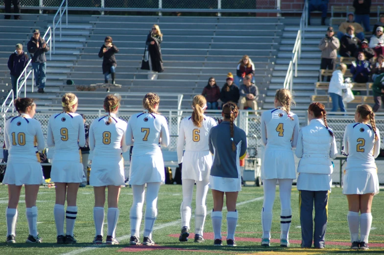 a group of girls in uniform standing on a soccer field