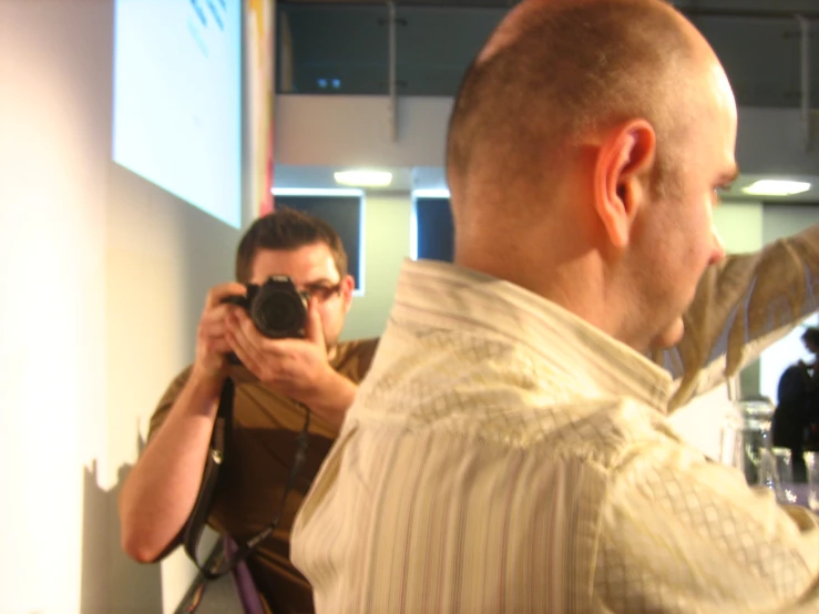 two people take pictures in the mirror while a man stands in front of them