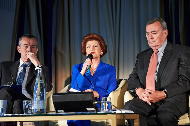 people sitting in a line talking on a stage