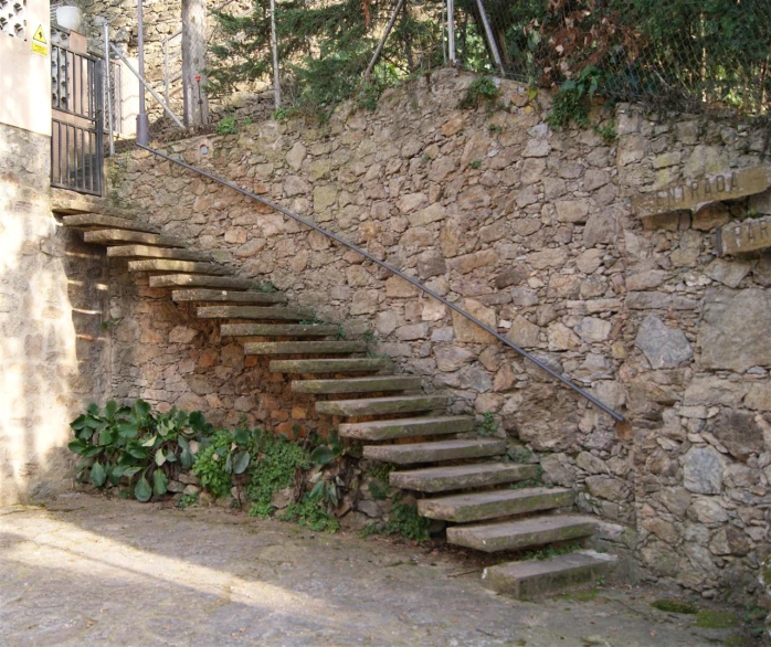 a set of stairs on a stone wall with foliage