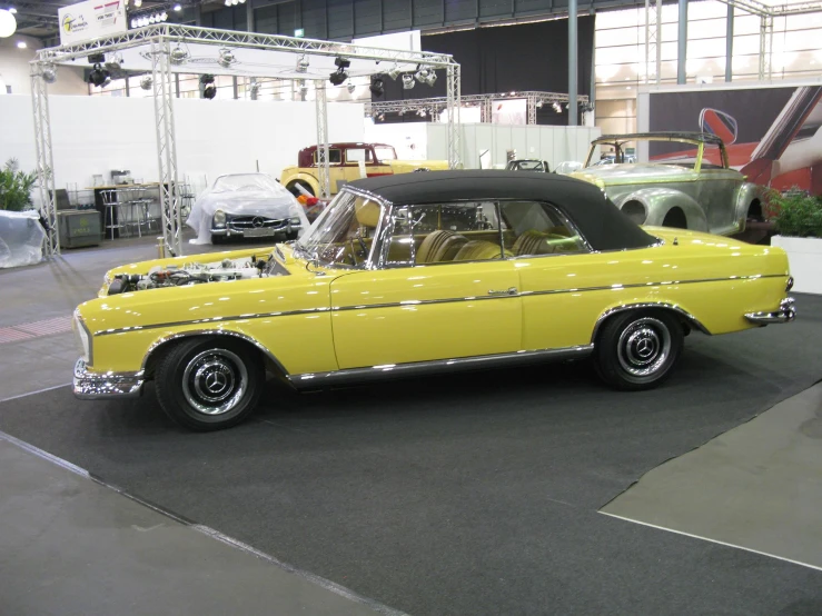 a yellow classic car parked on the display floor