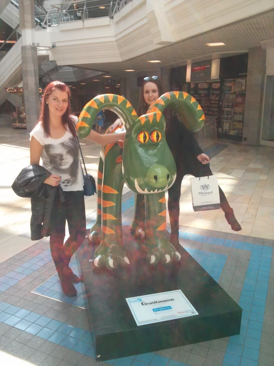 two girls are posing next to a dragon sculpture