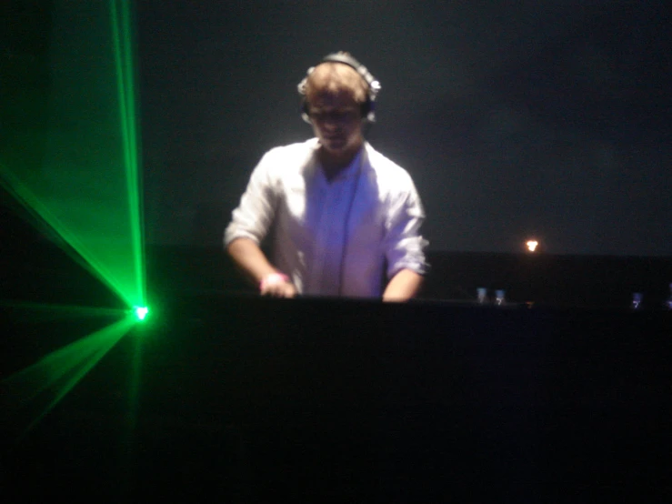 a man wearing headphones stands at the dj's console