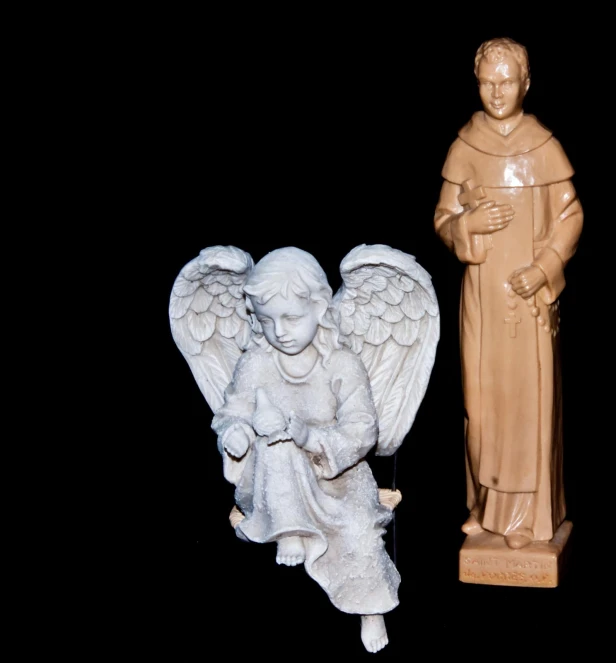 two ceramic figurines of an angel and a demon