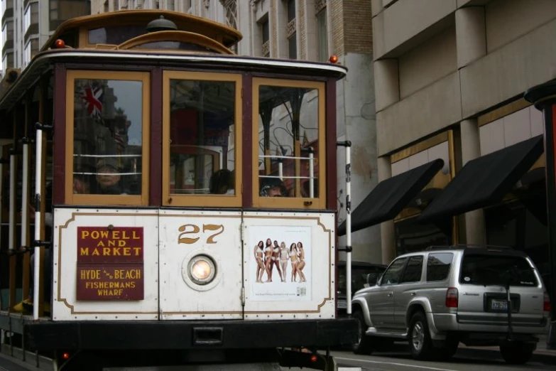 a cable car on street with white cars behind it