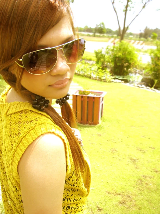 an asian woman wearing sunglasses on top of grass