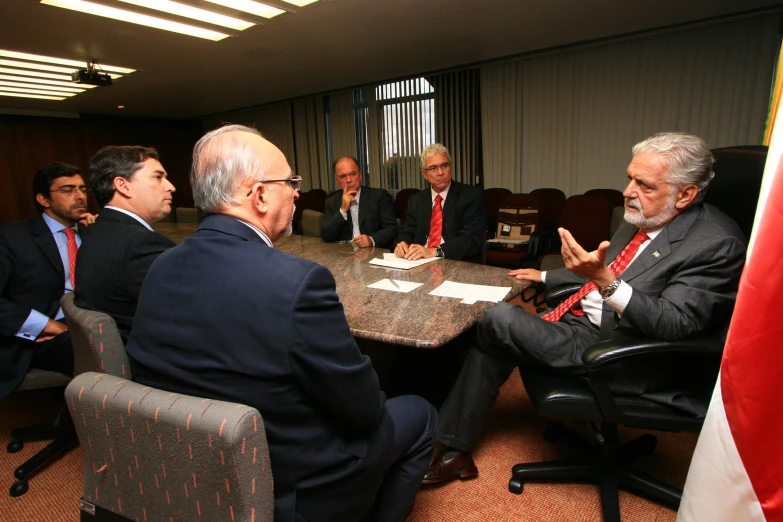 a group of men sitting around a table in suits