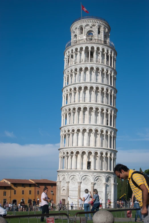 a man leaning down to look at the leaning tower