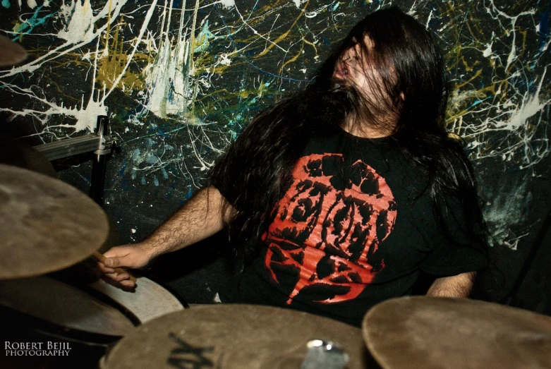 a drummer is drumming in front of a colorful wall