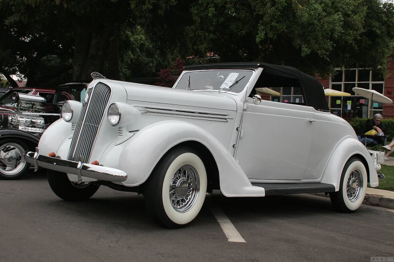 a vintage white car is parked in a parking lot