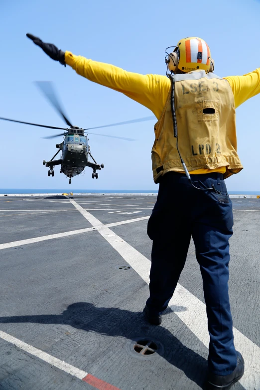 a man wearing a hardhat walking on a cruise ship with his arms spread wide