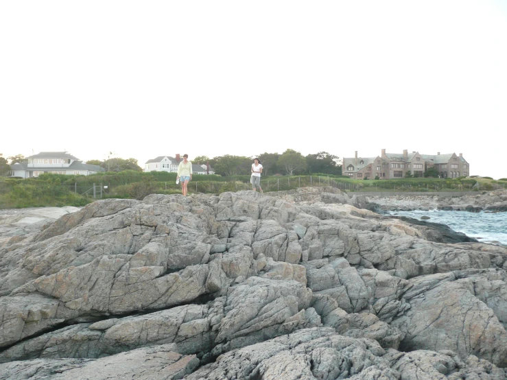 two people standing on rocks watching the ocean