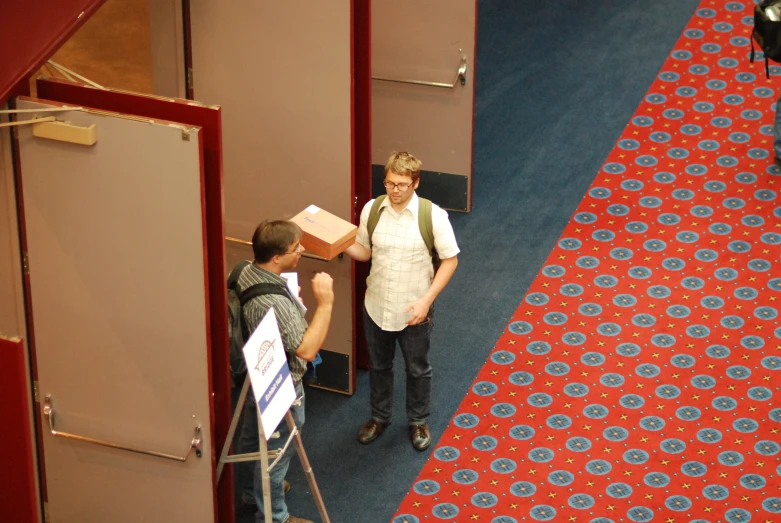 two men standing in an elevator with red carpet