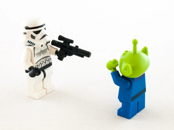 a star wars lego figure holding his arm up to another lego character with a gun