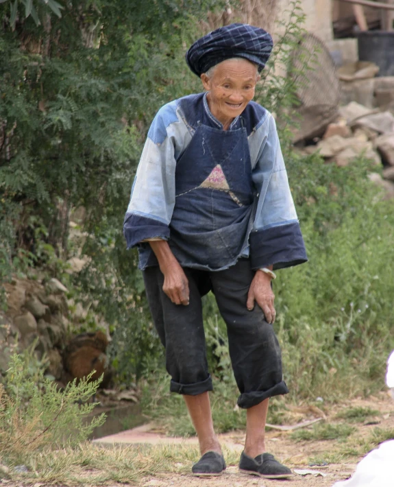 an older woman wearing denim pants and a hat