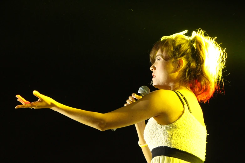 a woman holding a microphone while wearing a white dress