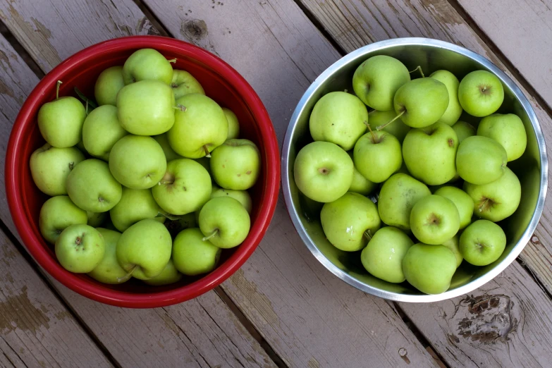 some buckets filled with green apples sitting on a table