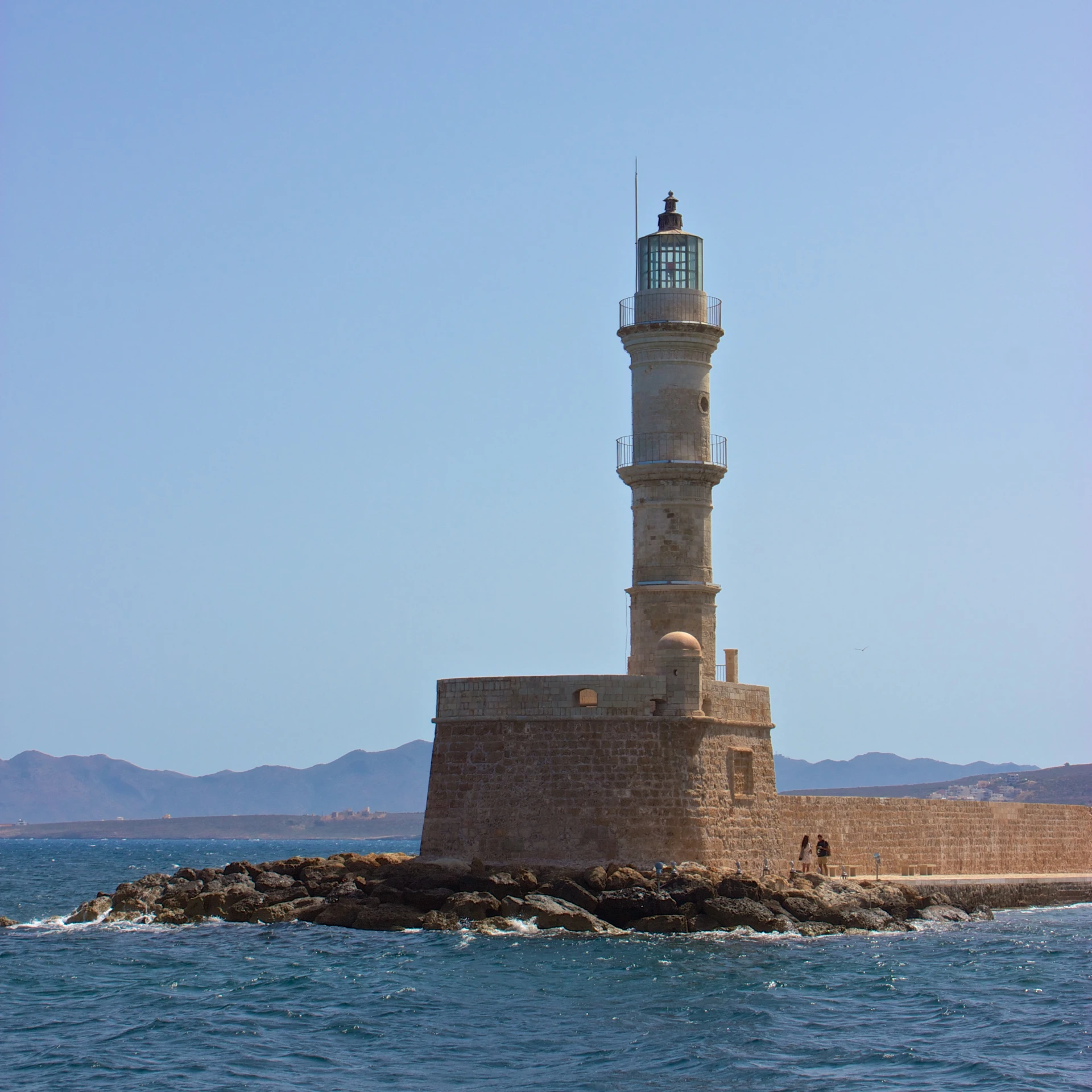 a lighthouse surrounded by rocks off the coast