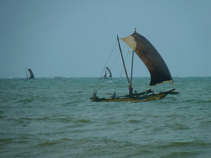 an old sailing boat with sails out in the ocean