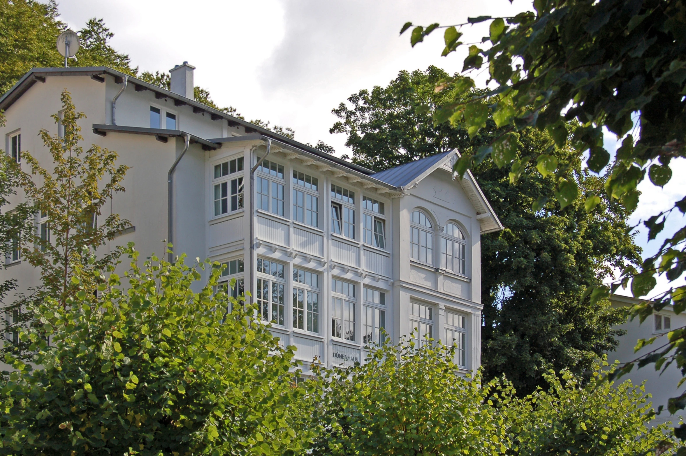 the white building is surrounded by trees and a blue sky