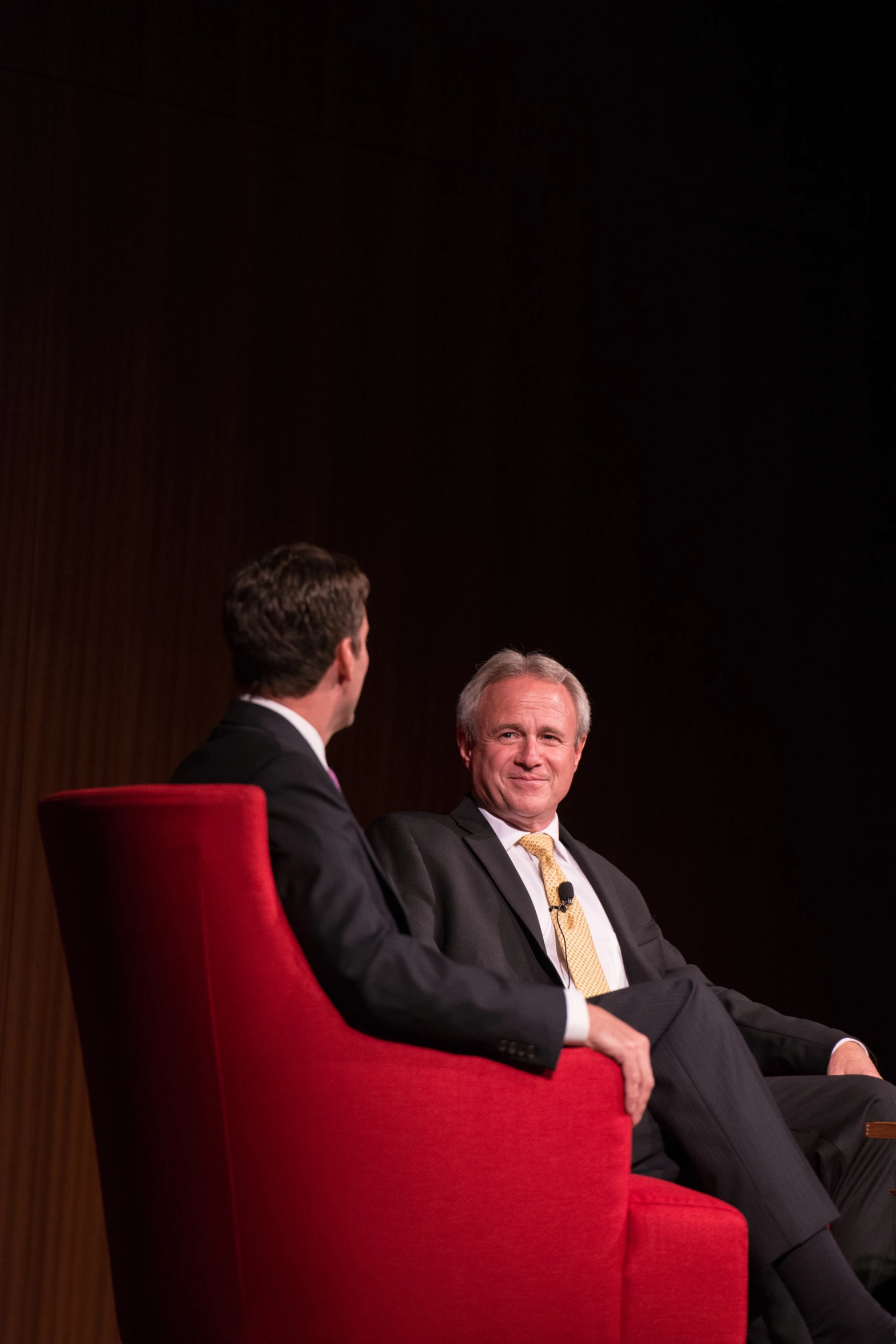 two men sit down in chairs facing one another