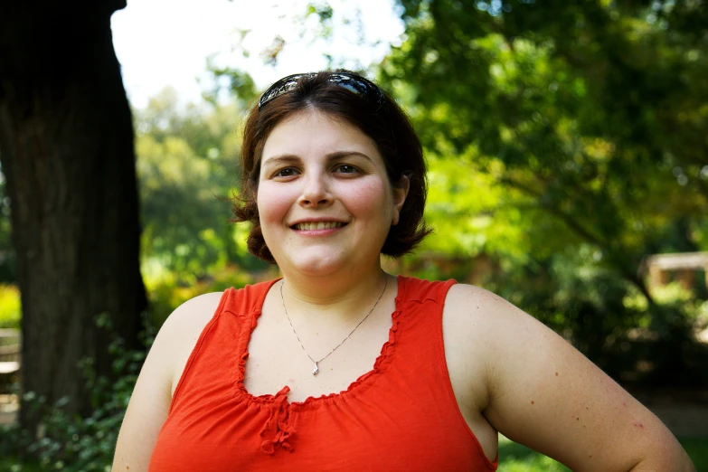 a woman in an orange top smiles for a picture