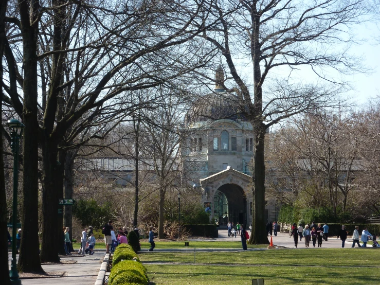 a group of people walking in front of trees and building