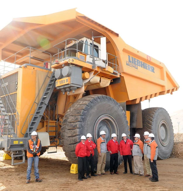 some people in hard hats are standing outside a dump truck