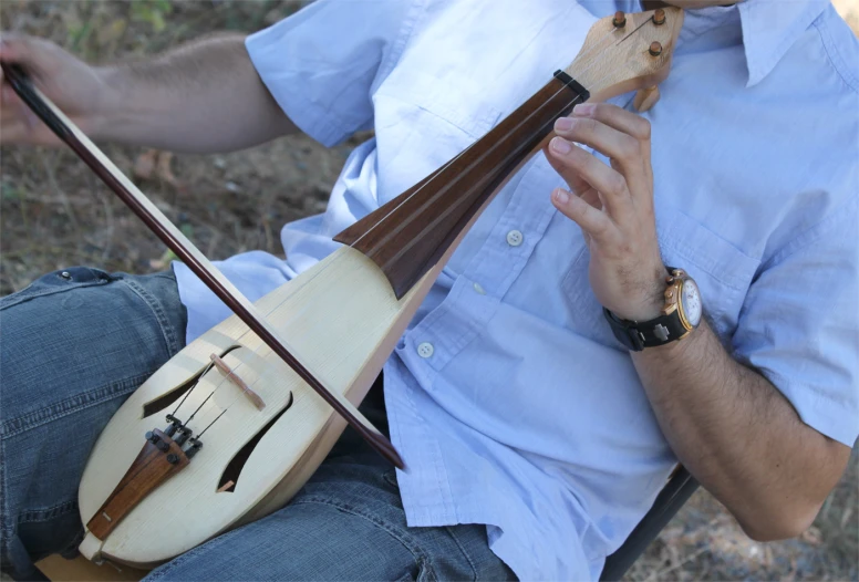 a man holding a guitar and wearing blue jeans