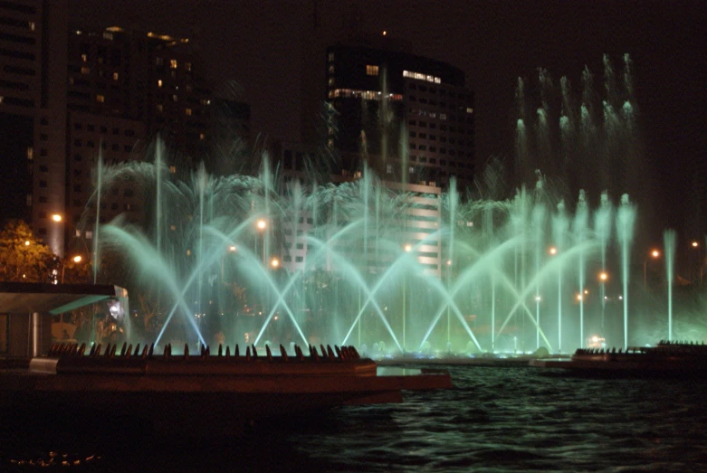 large green water fountains lit up in the night sky