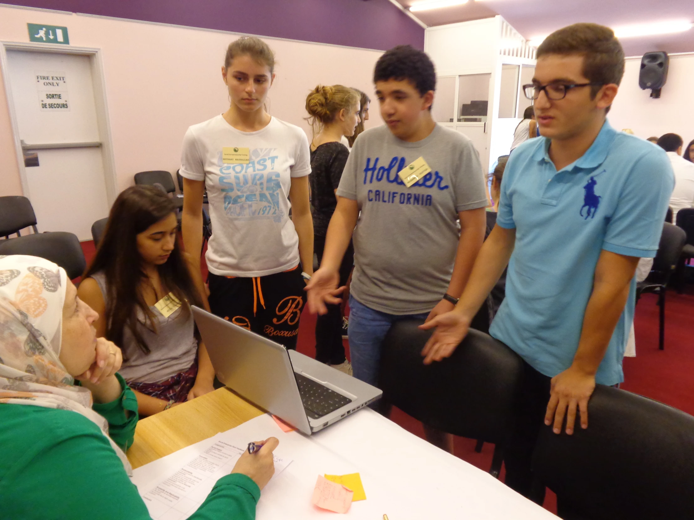 a group of students learning how to use a laptop